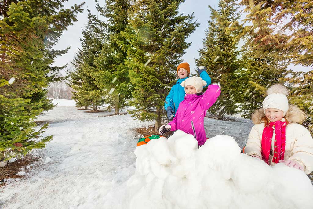 Foto på barn som leker med snöbollar utomhus i snön.