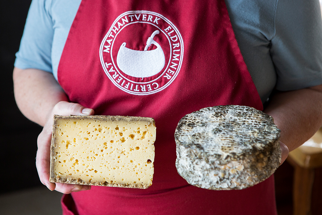 Foto på en persons överkropp som håller i en ost och ett bröd.