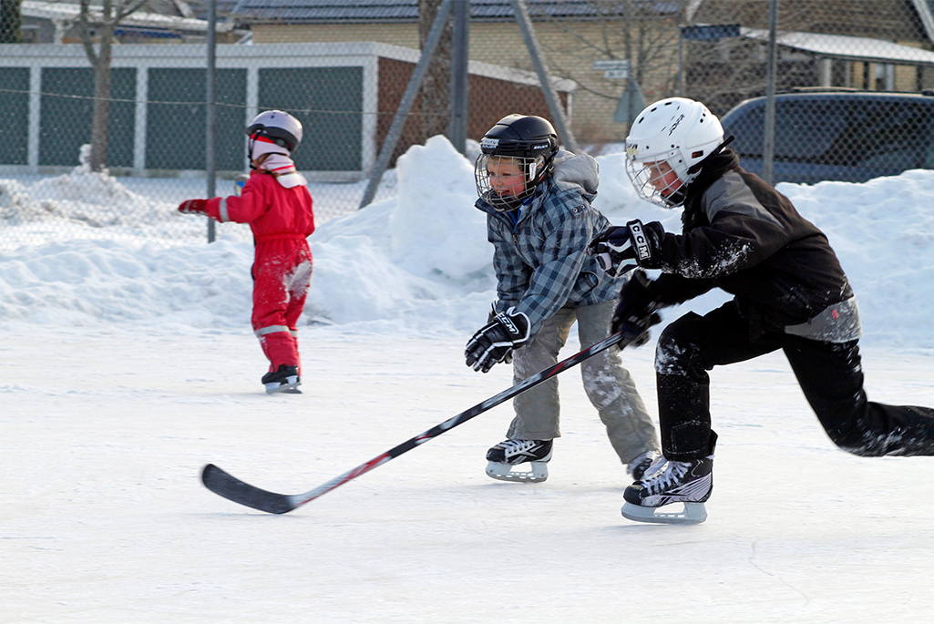 Barn som åker skidor och spelar hockey, foto.