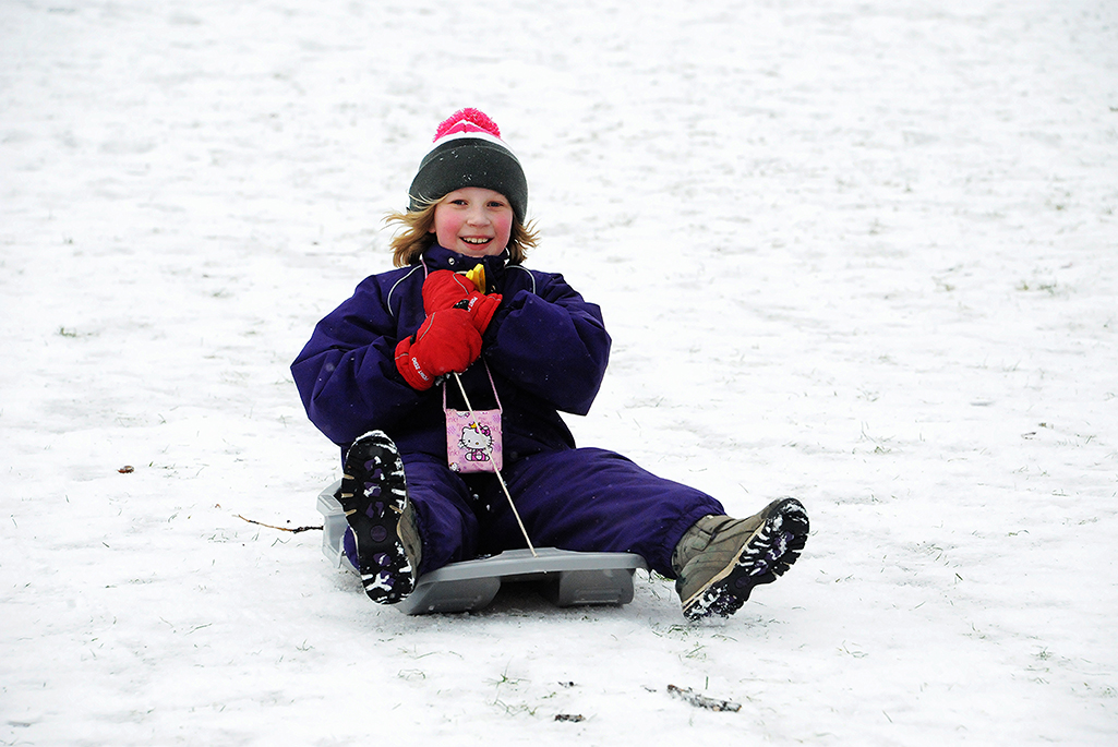 Foto på ett barn som åker pulka och ler. Foto: Sten-Åke Stenberg